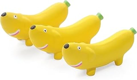 Three banana shaped dog toys with a dog face on them.