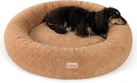 A dog is laying on a round dog bed.
