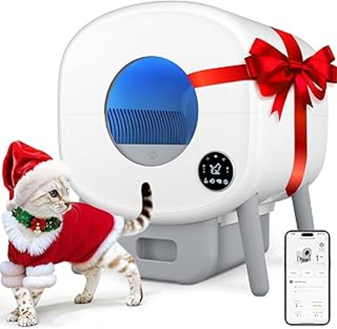 A cat wearing a Santa hat is standing next to a large capacity automatic litter box.
