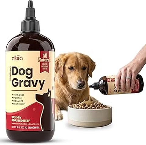 A bottle of dog gravy is poured into a bowl of food.