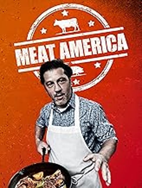 A man wearing a white apron and holding a spatula.